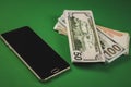 many packs of cash and phone lying on a green background