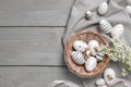 Many painted Easter eggs, branch with lilac flowers and ribbon on grey wooden table, flat lay. Space for text Royalty Free Stock Photo