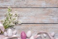 Many painted Easter eggs, branch of lilac flowers and ribbon on rustic wooden table, flat lay. Space for text Royalty Free Stock Photo