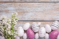 Many painted Easter eggs and branch of lilac flowers on rustic wooden table, flat lay. Space for text Royalty Free Stock Photo