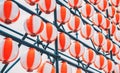 Many paper red-white oriental paper lanterns hanging in a row on blue sky background