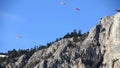 Many paragliders floating rock wall