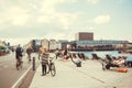 Many people chilling at riverbanks and riding cycles in center of modern city