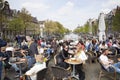 many people enjoy nice spring day outside near canal in Amsterdam