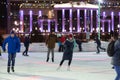 Many people skate in the evening on a city skating rink.