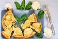 Many pieces of healthy cauliflower pie on the gray plate decorated with fresh basil leaves and vintage silver knife and fork Royalty Free Stock Photo