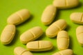 Many pills, antibiotics or vitamins yellow color on a green background close-up, close-up