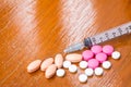 Many pills of shape are different color and syringe on wood table Royalty Free Stock Photo