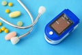 many pills, stethoscope, pulse oximeter for finger tip simultaneous monitoring of blood flow and transcutaneous oxygen on table Royalty Free Stock Photo