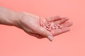Many pink pills in woman hand on pink background. Medical concept of medicine treatment, vitamins, supplements Royalty Free Stock Photo