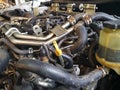 Many pipes in the engine room of the car that are dirty with oil stains.