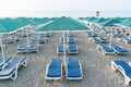 Many plastic deckchairs and umbrellas at the sea beach at sunrise. Summer vacation concept. Royalty Free Stock Photo