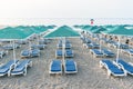 Many plastic deckchairs and umbrellas at the sea beach at sunrise. Summer vacation concept. Royalty Free Stock Photo