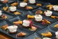 Many prepared appetizers of feta cheese and rhubarb with sprout garnish arranged on black plates for a festive gourmet menu, Royalty Free Stock Photo