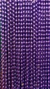 Many purple beads party neacklaces for celebrations or background. Macro close up vertical