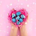 Many quail blue eggs. Paper heart shape nest in hands on pink with sparkle lights. Happy Easter love concept