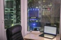 Many racks with computer equipment are behind the glass wall of a modern data center. Laptop is on the table in front of powerful Royalty Free Stock Photo