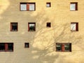 Many random placed windows on a yellow brick residential building outdoors. Royalty Free Stock Photo