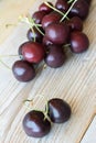 Many raw cherries on the wooden table. Two cherries with a twig in form of heart with some cherries nearby