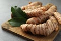 Many raw turmeric roots and green leaves on grey table, closeup Royalty Free Stock Photo