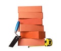 Many red bricks, trowel and tape measure on white background