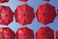 Many Red Coral Umbrellas Against The Blue Sky. View From Below. Abstract Background With Red Umbrellas.