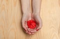 Many red hearts in women`s palms. Wooden background. Red nail polish