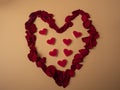 Many red petals from roses lie in the shape of a large red heart