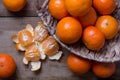 Many ripe mandarins in a basket. One peeled and divided into lobules