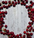 Many ripe red cherries on the branches lie in the form of a frame along the edges of a light wooden table Royalty Free Stock Photo