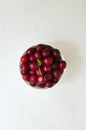 Many ripe red cherries in a white ceramic bowl on a light background. The concept healthy food. Vertical orientation. Top view Royalty Free Stock Photo