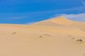 Many ripples wave lead to peak of sand dunes under sunny blue cloud sky in Nam Cuong, Phan Rang, Viet Nam.