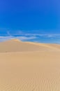 Many ripples wave lead to peak of sand dunes under sunny blue cloud sky in Nam Cuong, Phan Rang, Viet Nam.