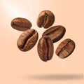 Many roasted coffee beans falling on beige background Royalty Free Stock Photo