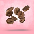 Many roasted coffee beans falling on pink background Royalty Free Stock Photo