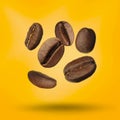 Many roasted coffee beans falling on yellow background Royalty Free Stock Photo