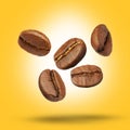 Many roasted coffee beans falling on yellow background Royalty Free Stock Photo