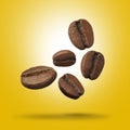 Many roasted coffee beans falling on yellow background Royalty Free Stock Photo