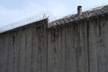 many rows of barbedwire, high concrete fence, barbed wire fence on top, building for execution of punishments for criminals, Royalty Free Stock Photo