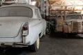 Many rusty abandoned forgotten antique oldtimer old car and motorcycles at junkyard factory storage warehouse indoors