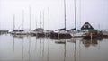 Many sailing yachts parked in the port of Marken with masts reflecting to a water in cloudy misty Day