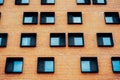 Many same quadratic windows on a modern brown brick building in daylight. Architecture concept. Strange window Royalty Free Stock Photo