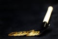 Many shiny golden coins pile on black shovel on black background, concept digging golden coins for