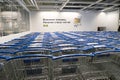 Many shopping trolleys with logo in IKEA store on background of inscription on the wall with proposal to take a cart in Russian