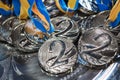 Many silver medals with blue yellow ribbons on a silver tray, awards of champions, sport achievements, second place, prize for the