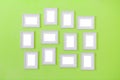 Many of simple white blank small picture frames hanging on green color wall background, copy space