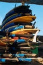 Many single fin surfing longboard with surf leash ready for rent. Set of multicolored surf boards in a stack by ocean. Surf Royalty Free Stock Photo