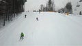 Many skiers and snowboarders descend down the mountain slope