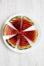 Many slices of fresh ripe grilled watermelon on a white round plate over white wooden background, from above. Healthy summer fruit Royalty Free Stock Photo