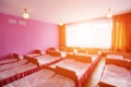 Many small beds with fresh linens in the kindergarten preschool empty bedroom interior for a comfortable afternoon sleep for Royalty Free Stock Photo